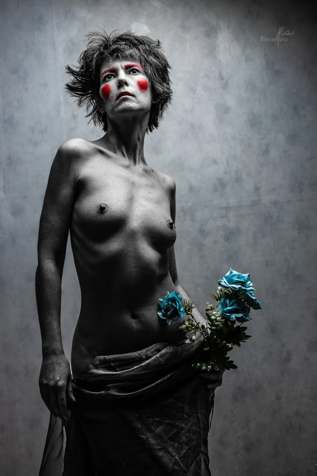 Nudo artistico con trucco rosso sulle guance e rose azzurre