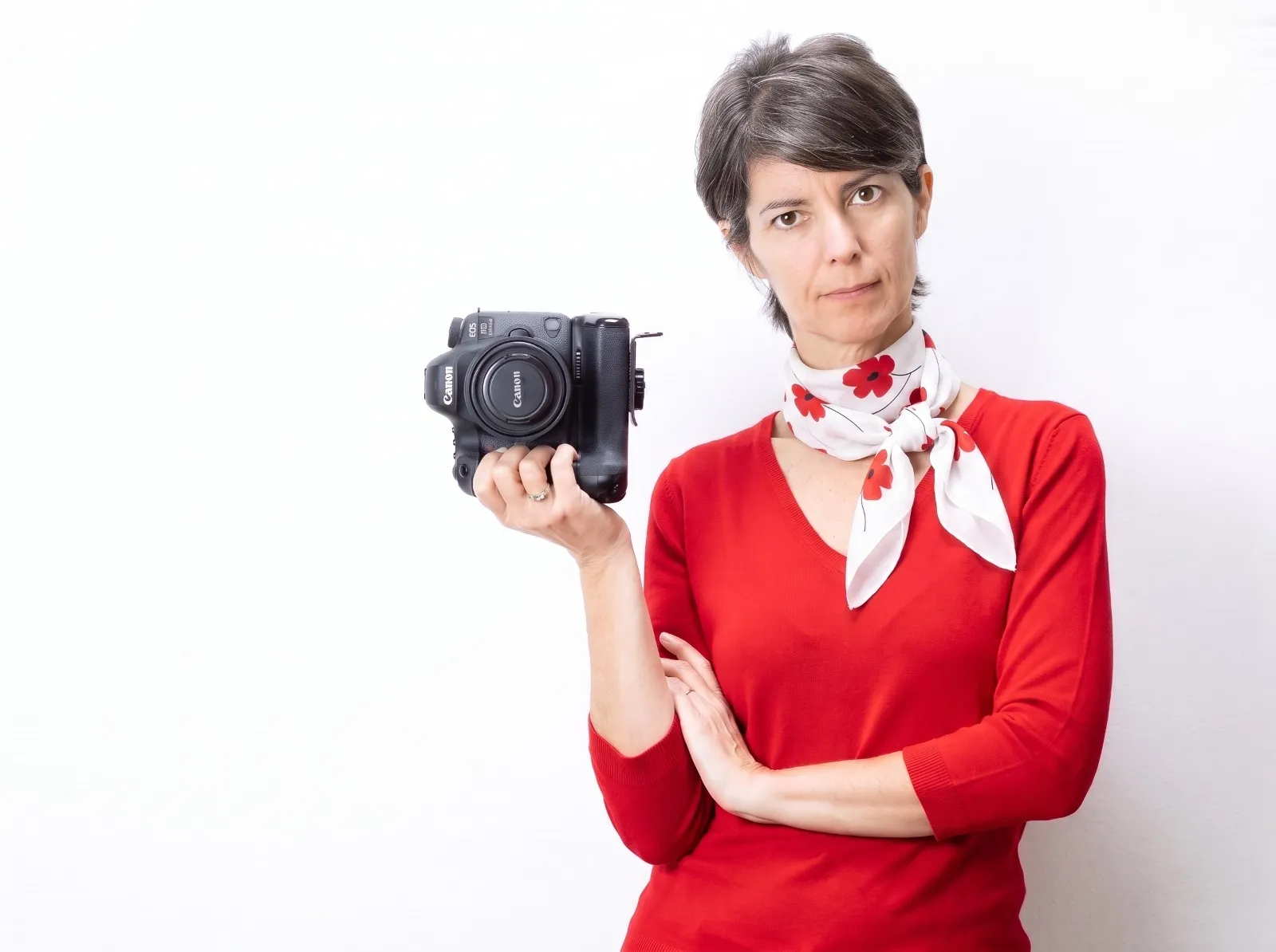 Ilia Da Lozzo con la macchina fotografica su fondo bianco, maglia rossa e foulard a fiori