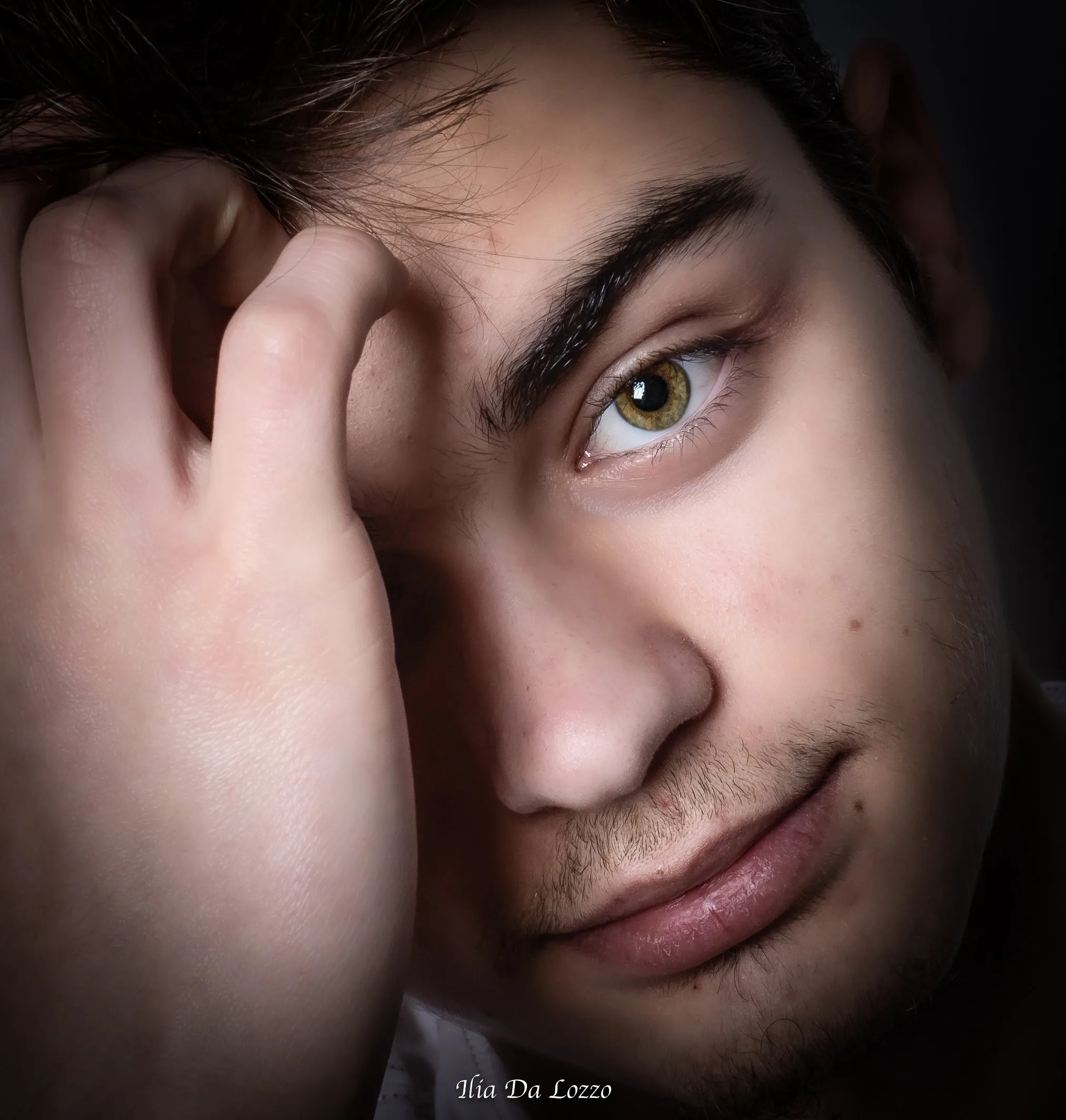 Ragazzo con la mano sulla fronte, occhio verde in luce