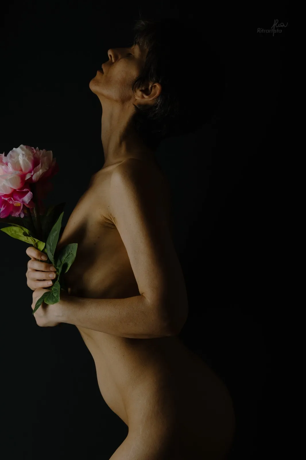 Nudo di profilo con peonia rosa, sguardo verso l'alto