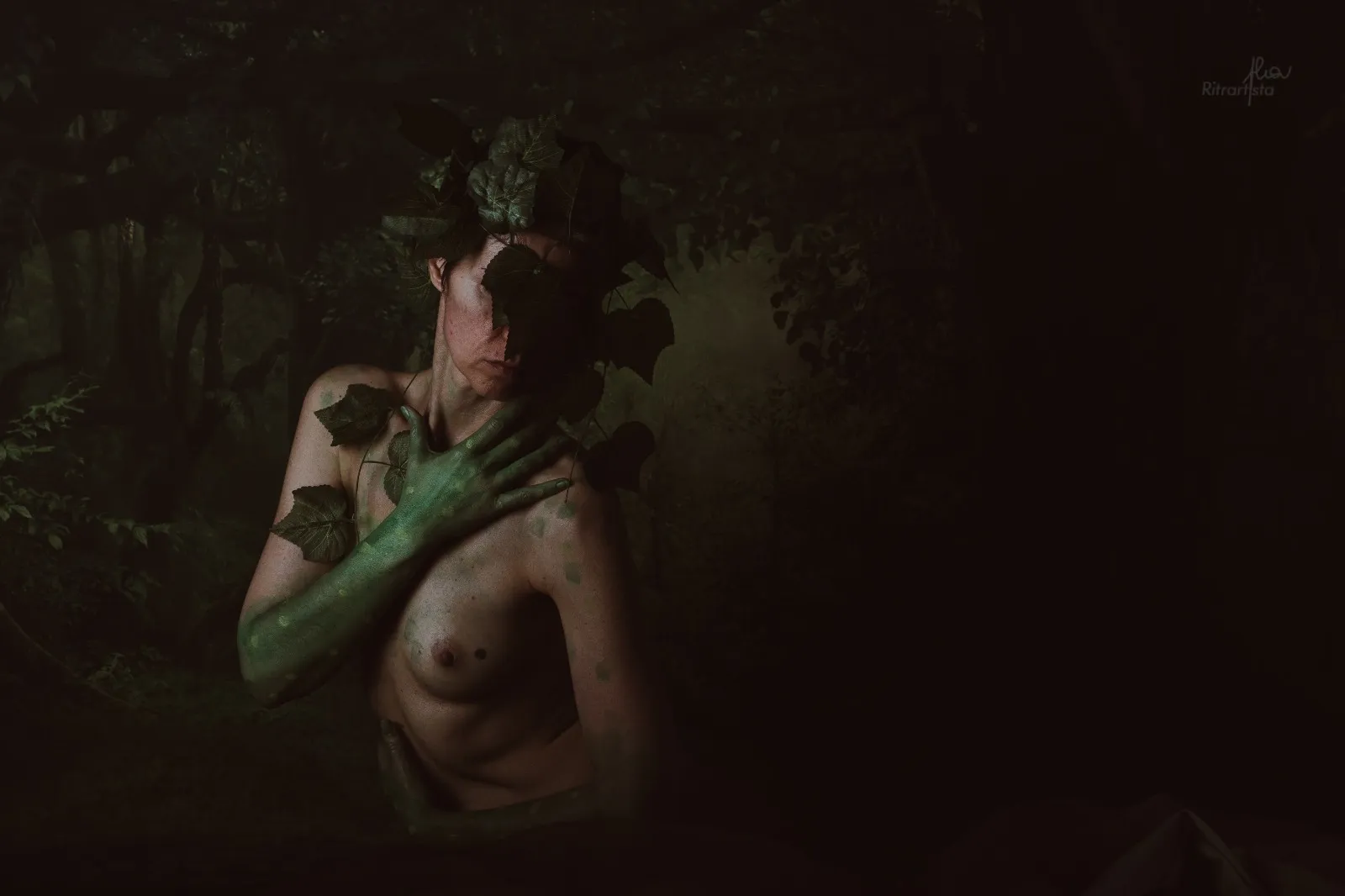 Nudo artistico nel bosco con foglie d'edera e braccio dipinto di verde