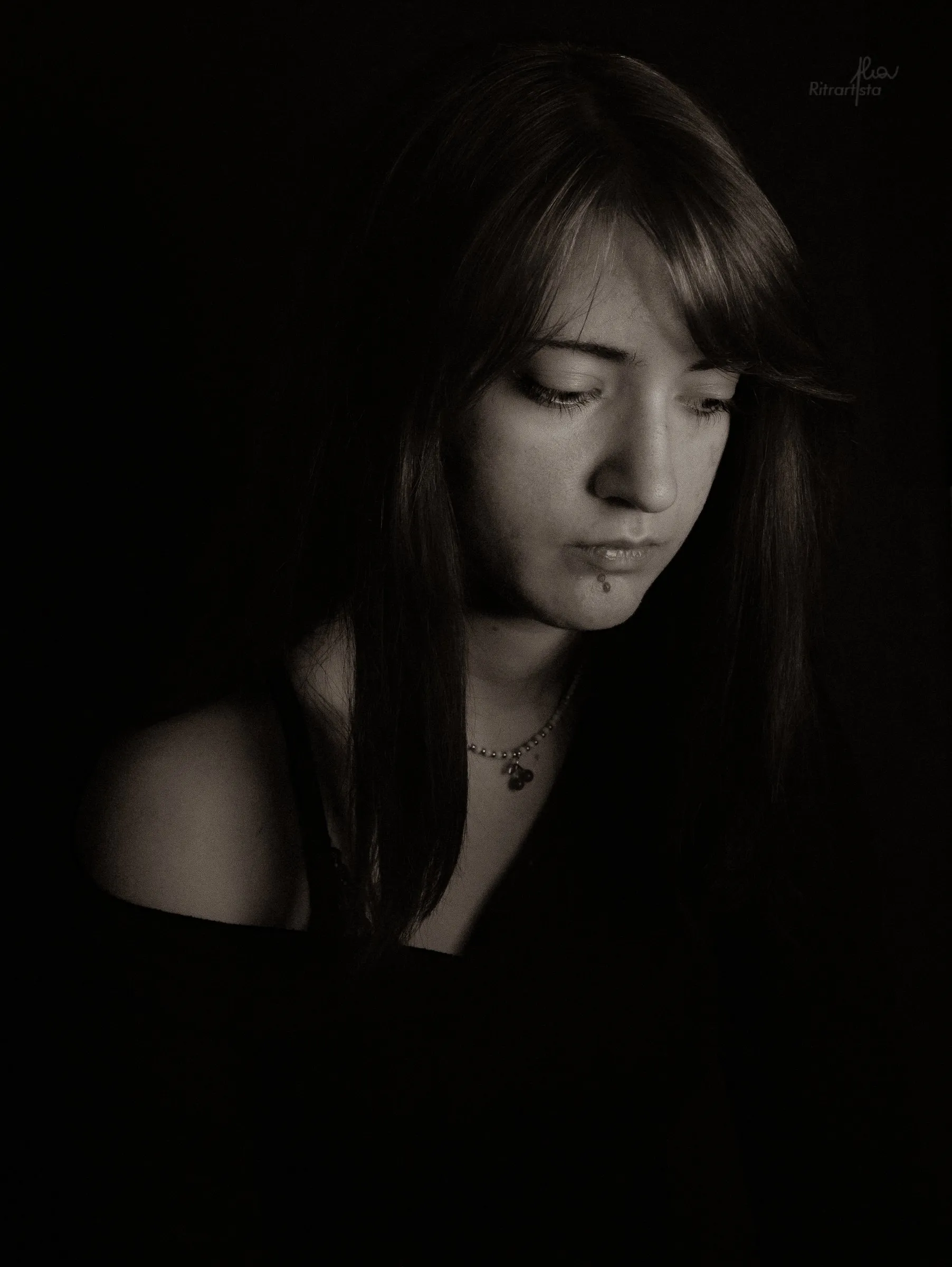 Ragazza che emerge dall'ombra, sguardo basso